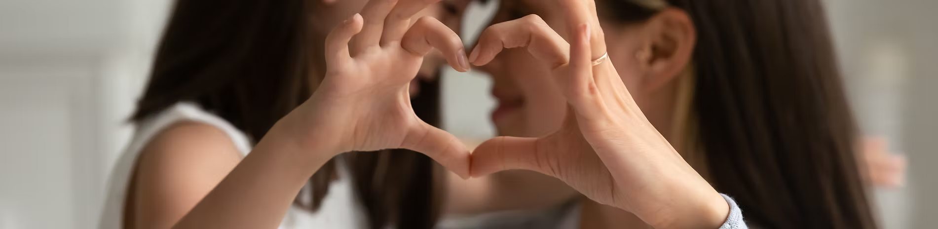 A parent and child making a heart shape with their hands